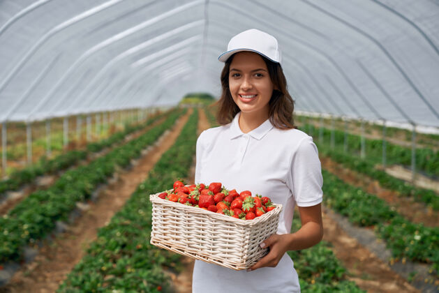女人微笑的黑发女人手里拿着一篮草莓水果种植浆果