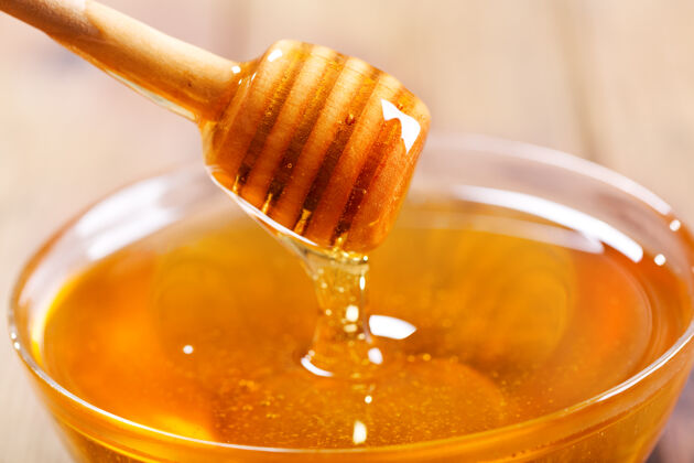 倾倒把蜂蜜倒进木桌上的碗里液体木材美味