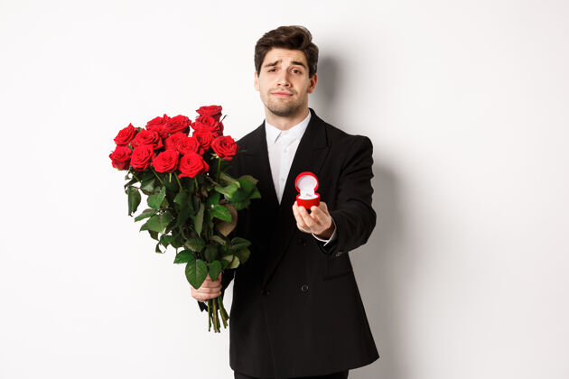 帅哥穿着黑色西装 手持玫瑰和订婚戒指 面带微笑的帅哥夹克订婚男人