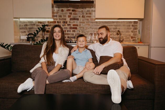 家庭爸爸 儿子和妈妈在公寓的沙发上饶有兴趣地看电视男性沙发肖像