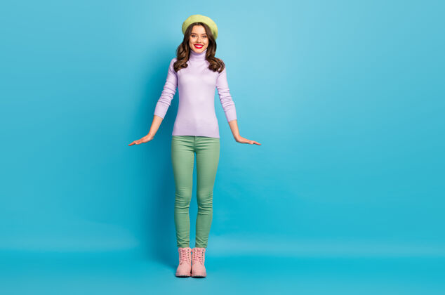 调情漂亮漂亮的女士的全长照片时尚的外观好心情步行街穿现代绿色贝雷帽紫色高领套头衫裤子鞋子孤立的蓝色墙壁头饰秋天时尚