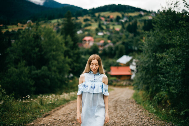 乡村年轻迷人优雅的金发碧眼女孩 身着蓝色连衣裙 在乡间的马路上摆姿势年轻服饰乡村