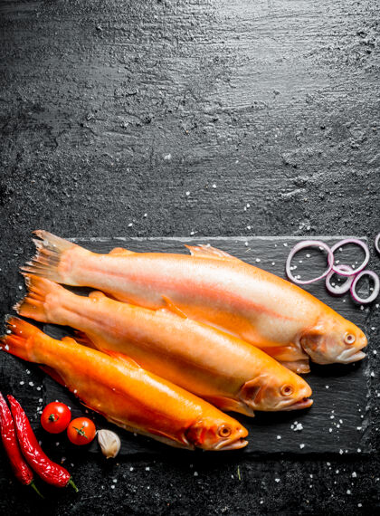 鲑鱼生鳟鱼配辣椒 西红柿和洋葱圈放在黑色乡村餐桌上辣椒黑色胡椒