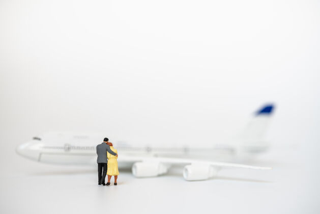 情侣夫妻 家庭和旅游概念男女微型人物人们拥抱并走向迷你飞机模型拥抱旅行男性