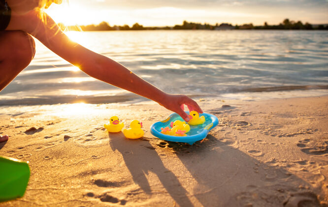 快乐在蓝色的小水池里 坐在海边 一个认不出来的白人小孩的手在玩橡皮黄鸭子旅游鸭子自然