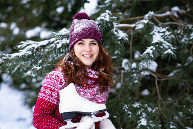 靴子肖像画在雪林里 一个快乐的女人肩上扛着冬天的溜冰鞋冬季乐趣和运动女人寒冷圣诞节