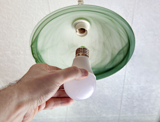 安装近景节能led灯泡在人的手中 取代了灯具在天花板上的绿色磨砂玻璃制成吊灯霜冻低能耗