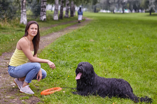 狗布莱克·布里亚德躺在公园的空地上 旁边有个年轻女子家畜可爱成人