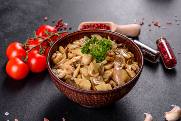 晚餐新鲜美味的辛辣蘑菇罐头与香料和草药在陶瓷菜肴在黑暗的混凝土背景菜开胃菜装饰
