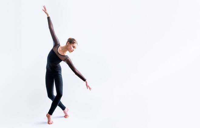 瘦身一个穿着黑色紧身套装的芭蕾舞女孩在白色背景上跳舞 现代的舞蹈设计女孩舞蹈实践