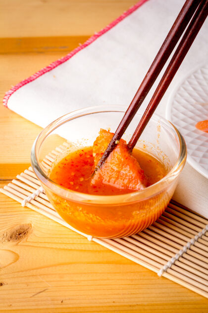 晚餐用木筷从海鲜酱碗里捞起的新鲜三文鱼蘸背景健康食物
