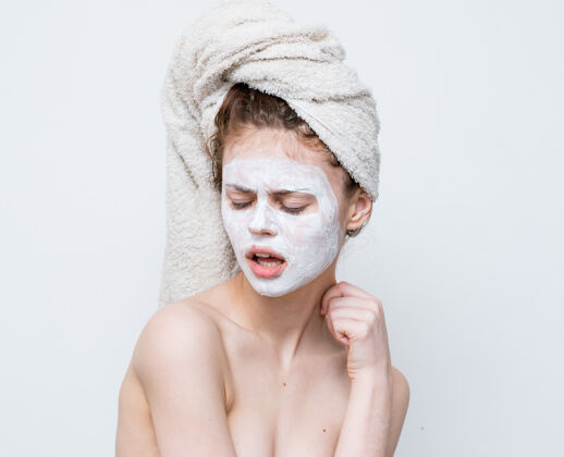 生活方式光着肩膀的女人头上戴着毛巾护肤面膜脸痤疮面部