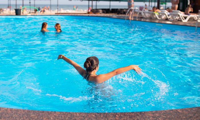 户外顶视图：不明身份的年轻女孩 在明亮的阳光下 快乐地在蓝色清澈的池水里溅水孩子水娱乐