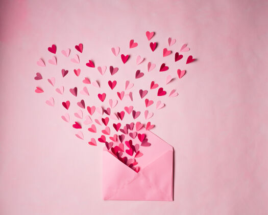 形状红色和粉红色的纸心在打开的粉红色信封上粉红色信工艺