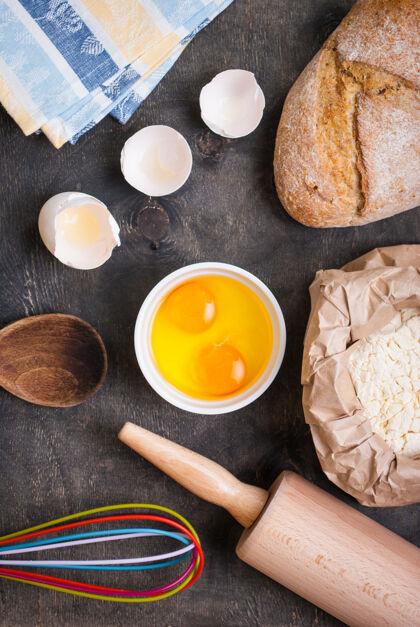 勺子烘焙的配料 蛋壳 面包 面粉和擀面杖 放在黑桌子上卷面团蛋糕