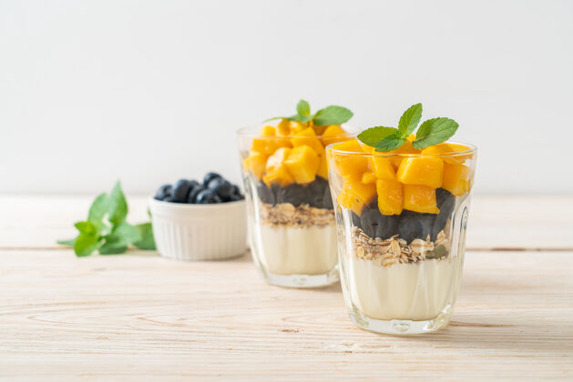 热带自制新鲜芒果和新鲜蓝莓配酸奶和果汁健康麦片美食风格椰子超级食品食物