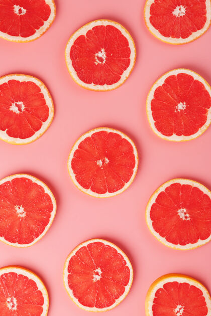 扁平粉红色背景上的多汁葡萄柚片图案 美丽的图案创意切片新鲜