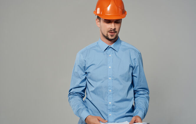 信心男建筑师戴着橙色的安全帽 工作着灰色的墙 看不见风景安全帽职业站