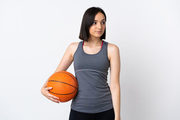 爱好打篮球的年轻女子孤零零地站在白墙上望向一边青年头女