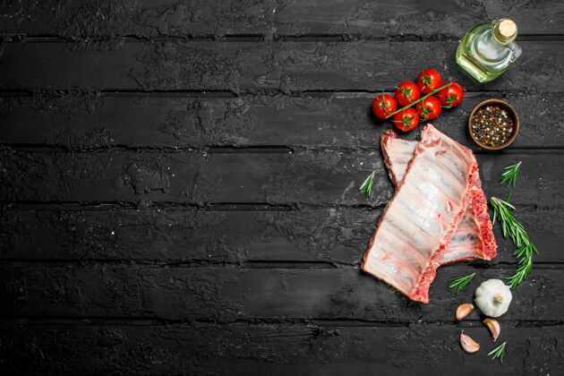 迷迭香在深色的乡村餐桌上放着番茄和香料的生排骨视图木头烧烤