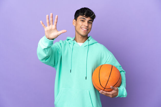 手指年轻人在孤立的紫色墙壁上打篮球 用手指数到五人五点