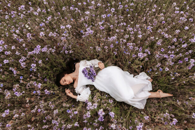 享受一个年轻漂亮的女孩闭着眼睛躺在一片盛开的田野里普罗旺斯浪漫气氛美丽年轻女性