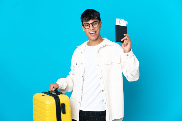 旅行带着手提箱和护照度假的蓝色背景的年轻人帅哥身份证旅行