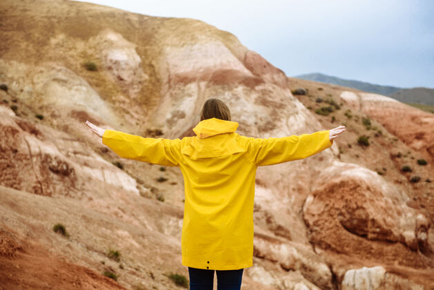 游客在阿尔泰火星山脉的背景下 一个举起双臂的女人旅行者悬崖旅行
