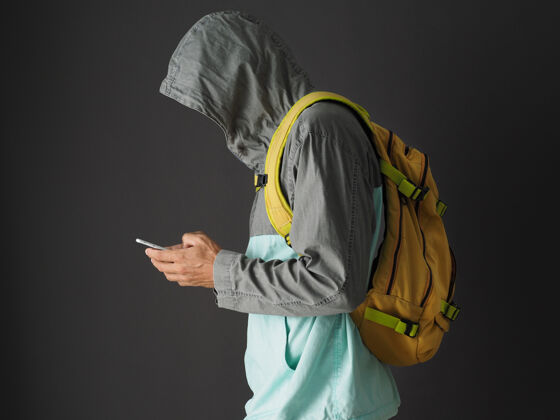 认不出来无法辨认的男子穿着运动衫连帽衫和黄色背包使用智能手机室内现代站