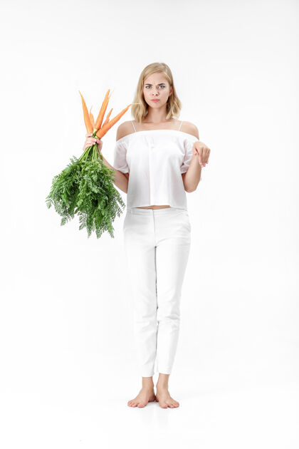 肖像美丽的金发女郎展示着兔子 手里拿着一根新鲜的红萝卜 红萝卜上有绿叶背景.健康还有节食健康自然一