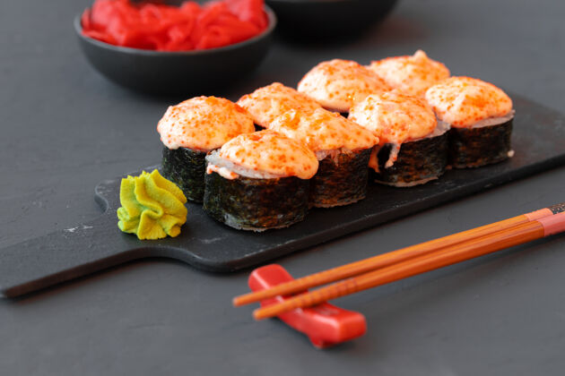 烘焙烤寿司卷放在木桌上的黑盘子里深色海鲜Maki
