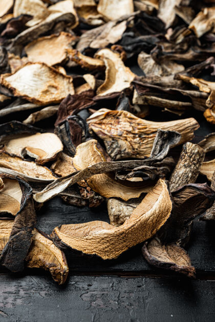 深色木材把切碎的野生干蘑菇放在旧的深色木桌上食物有机植物学