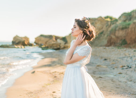深色穿着豪华婚纱的时尚新娘模特在海洋或海边礼服女人姿势