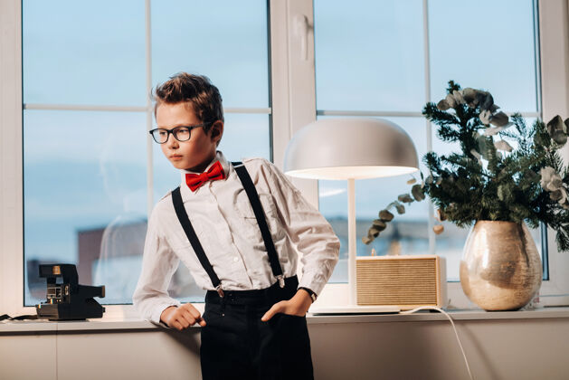 窗台一个男孩站在窗前 穿着一件衬衫 打着一条红领结 戴着一副眼镜白衬衫孩子老式