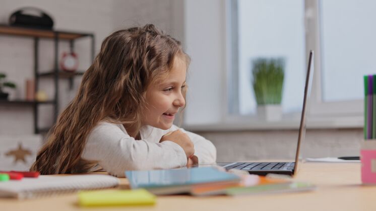 生活方式快乐可爱的小女孩在电视上欣赏她最喜欢的卡通画的肖像笔记本电脑微笑小学生在电脑上看视频小情绪学习