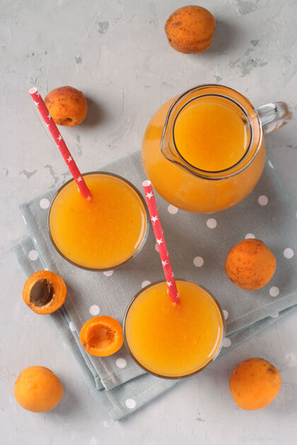 传统杏汁果肉在两个玻璃杯和一个罐子上的灰色表面 垂直格式 从上面看杏子草药顶视图