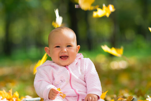玩耍在一个秋天的公园里 小女婴笑着玩着从天上掉下来的五颜六色的黄叶季节婴儿人