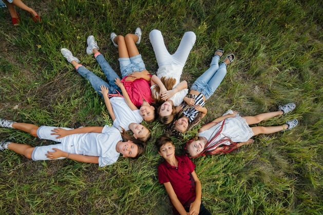 微笑一群快乐的孩子躺在草地上围成一个圈 开心地笑着团队圈子女孩