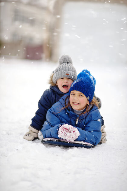 笑快乐的兄妹在雪上玩耍速度雪橇兴奋