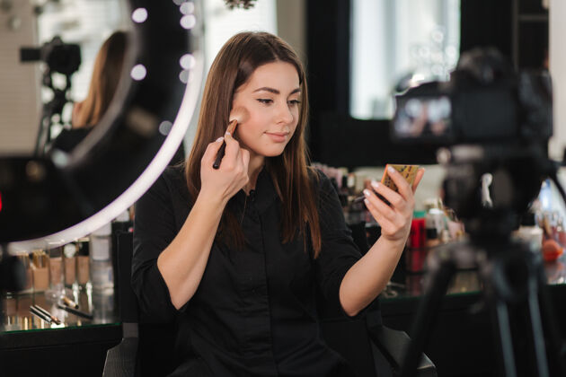职业年轻漂亮的女人和专业的化妆师博客记录化妆教程在工作室摄影数码相机化妆刷