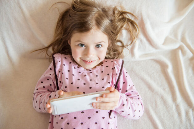 笔记本电脑手持平板电脑的可爱小女孩俯视图房子手持房间