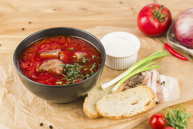 肉把罗宋汤放在盘子里 放上猪油 面包和葱 放在浅色的木头表面 特写传统罗宋汤餐
