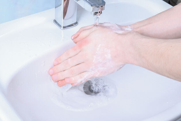 感染洗手池里用肥皂擦手的男人为电晕病毒倾倒手指皮肤护理