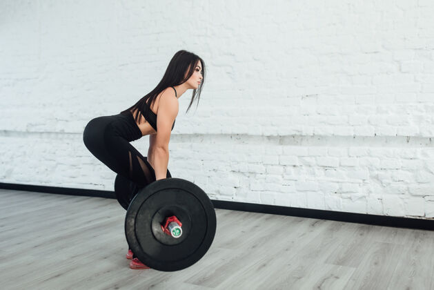 身体自信的年轻女子在健身房做举重锻炼转身回来的照片人运动准备