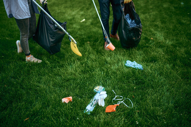 肮脏两个男人在公园里用袋子收集塑料垃圾 做义工人森林容器