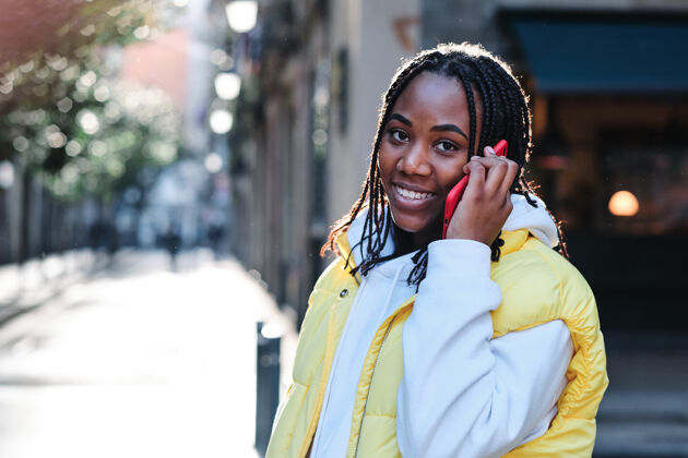肖像一位非洲裔美国妇女站在户外 一边微笑一边讲电话街道.城市以及沟通理念生活方式电话通信