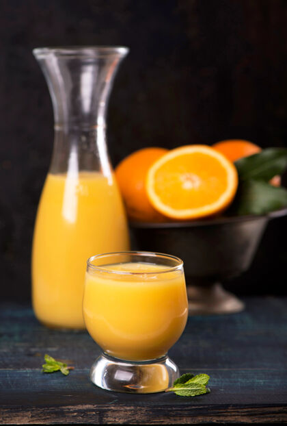 一半一杯鲜橙汁和新鲜水果放在木桌上乡村美味柑橘