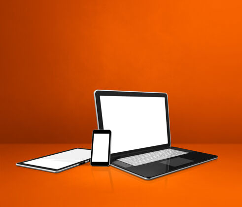 技术橙色办公桌上的笔记本电脑 手机和数字平板电脑屏幕橙色灯光