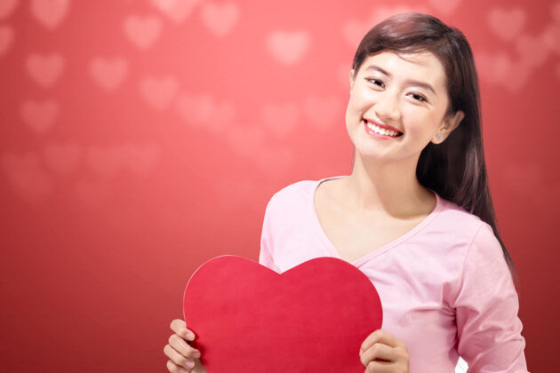 情人节一个亚洲女人拿着一颗红色的心墙情人节礼物天哪在一起微笑女人