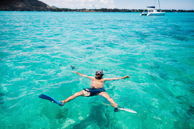 竖起大拇指一个戴着鱼鳍和面具的家伙在毛里求斯岛的泻湖里游泳运动热带泳装